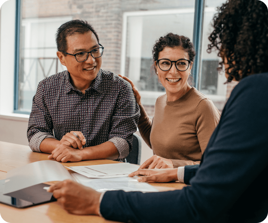 Two people sitting at a table with documents, engaged in discussion with a professional.